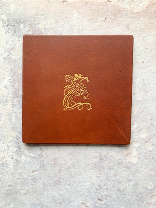 tan leather coasters with Estelle Manor logo in gold.