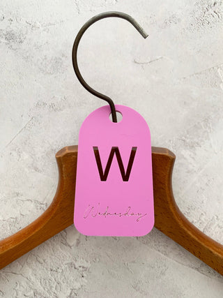 Pink Wednesday hanger label on a coat hanger.