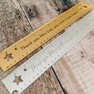 Two metallic acrylic rulers with personalized messages, one in gold with 'Thank you Mrs Lee' and the other in silver with 'Thank you Miss Lee', both adorned with star graphics.