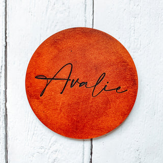 Engraved tan leather coaster with Avalie written on it in script writing.